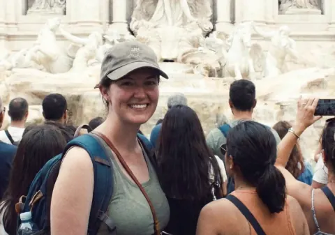 After: the same crowded fountain selfie with only the woman in the cap