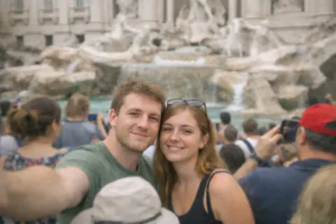 Before: a couple's selfie in a crowd in front of a large stone fountain, the woman with sunglasses on her head